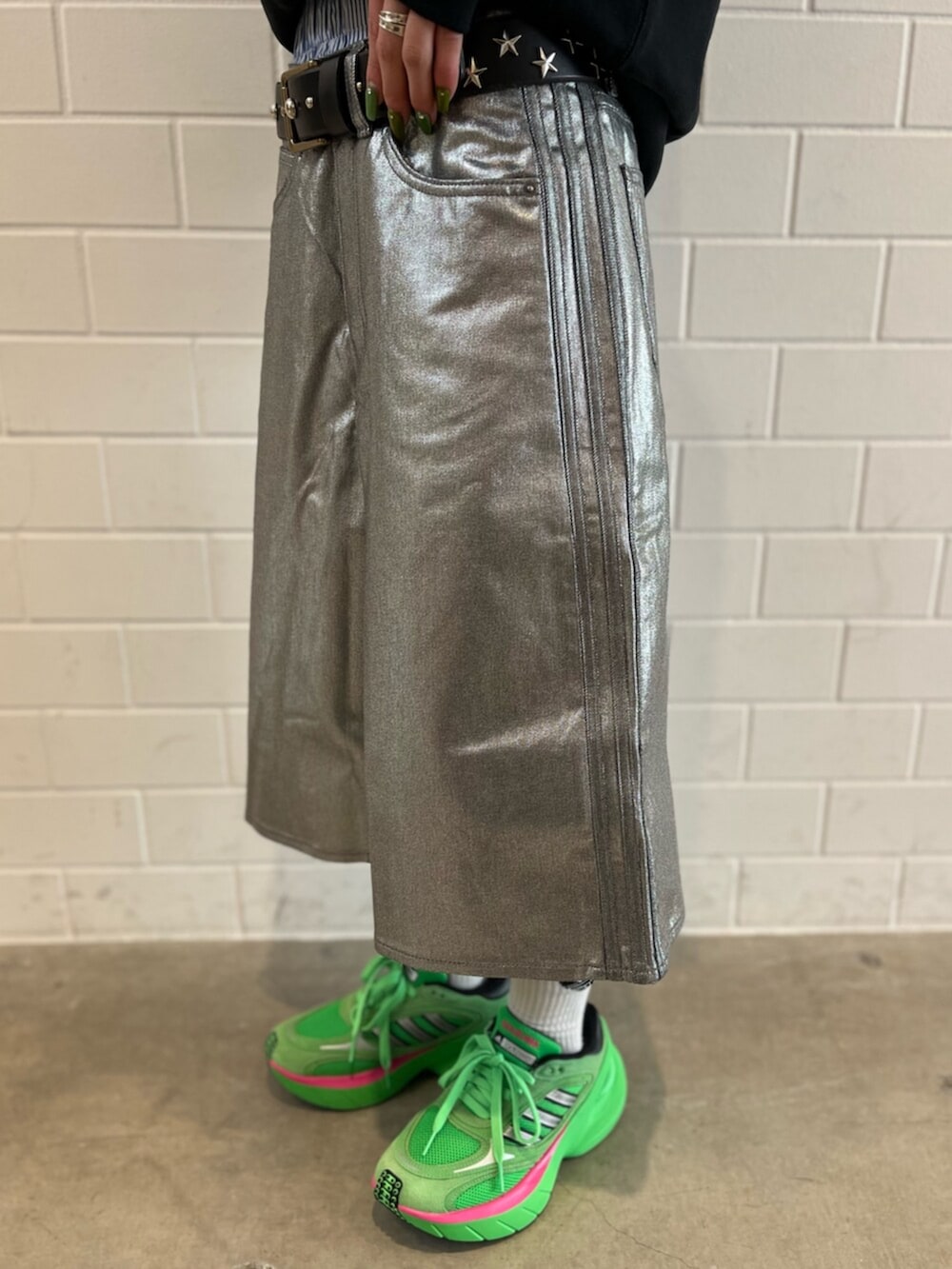 ブラック系のパーカー、グリーン系のシューズ、シルバー系のデニムパンツを着用したレディースの冬コーディネートの5枚目の写真