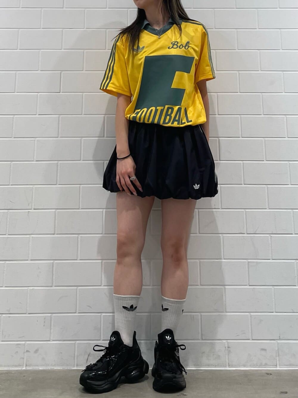 ブラック系のスカート、イエロー系のトップス、ブラック系のスニーカーを着用したレディースの冬コーディネートの2枚目の写真