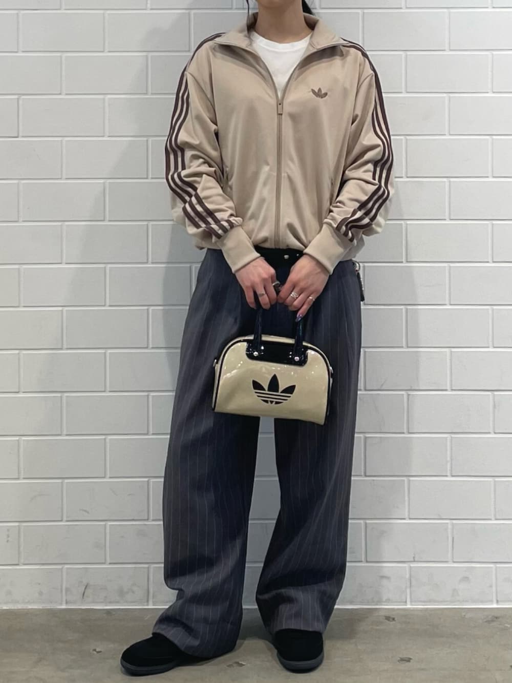 ブラック系のスニーカー、ベージュ系のトップス、ベージュ系のショルダーバッグを着用したレディースの春コーディネートの2枚目の写真