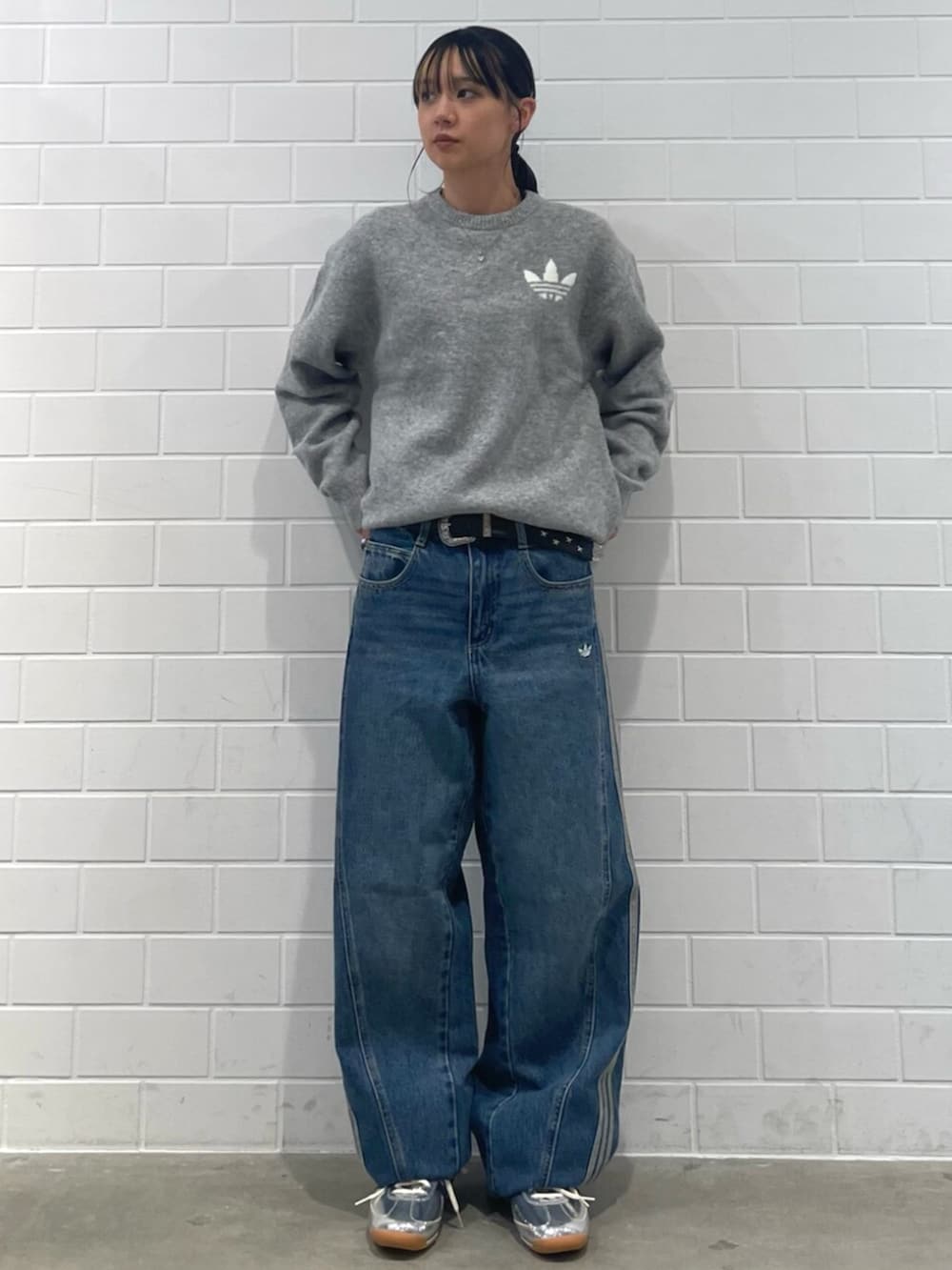 シルバー系のスニーカー、ブルー系のデニムパンツ、グレー系のニット/セーターを着用したレディースの秋コーディネートの3枚目の写真