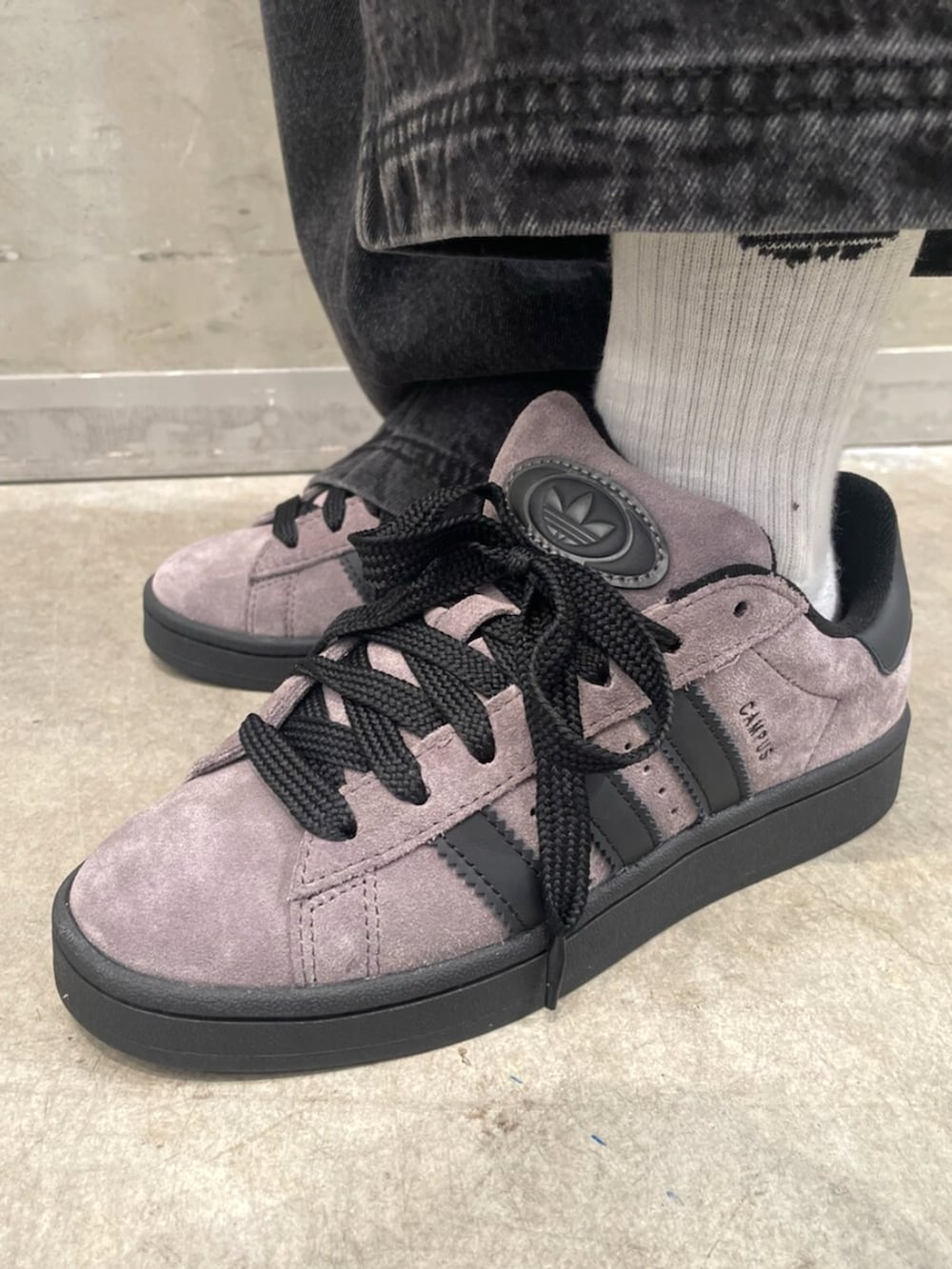 ブラウン系のスニーカー、グレー系のトップス、ブラック系のデニムパンツを着用したレディースの秋コーディネートの6枚目の写真