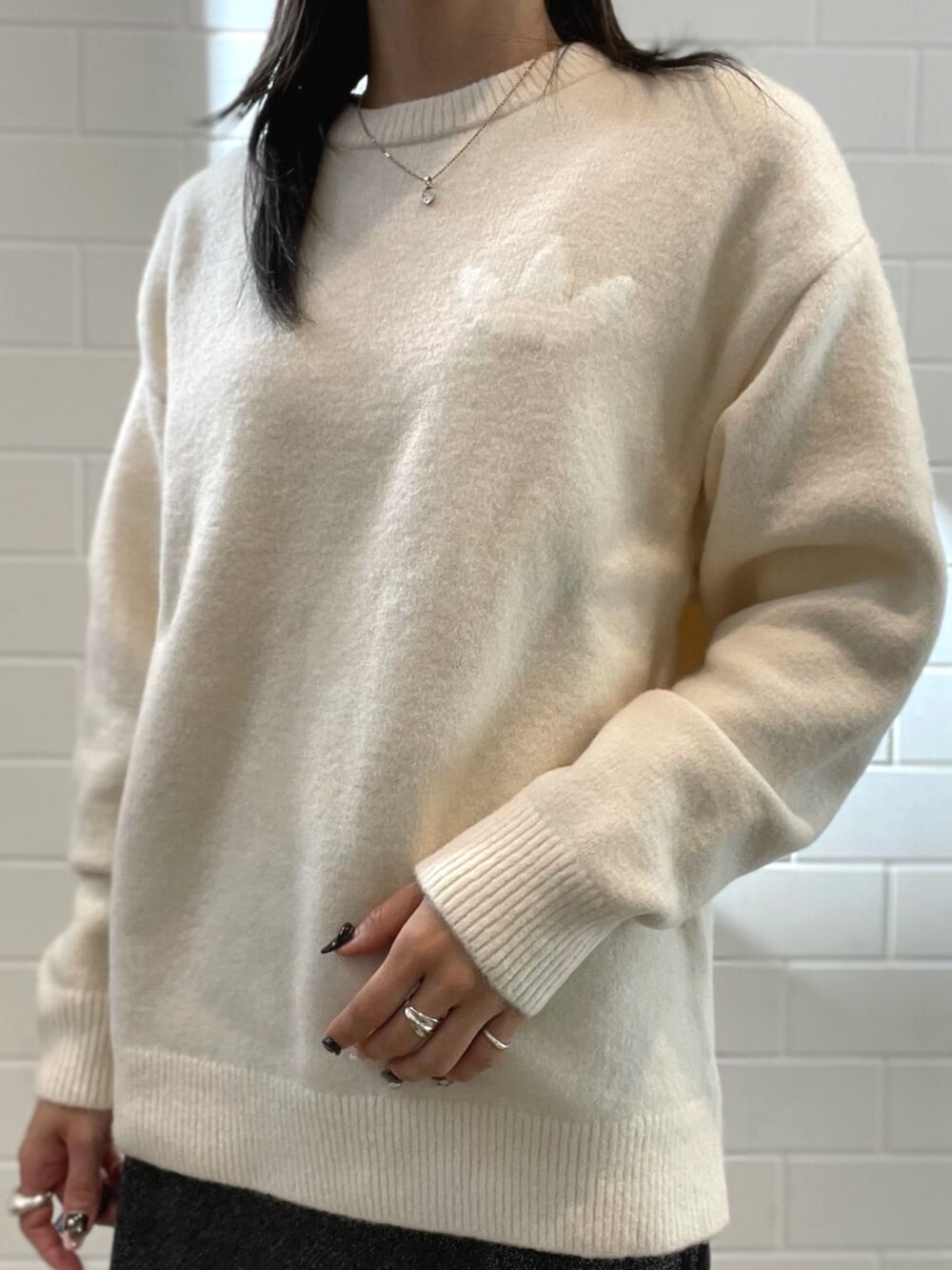 ブラック系のショルダーバッグ、ホワイト系のニット/セーター、ブラック系のスニーカーを着用したレディースの秋コーディネートの3枚目の写真