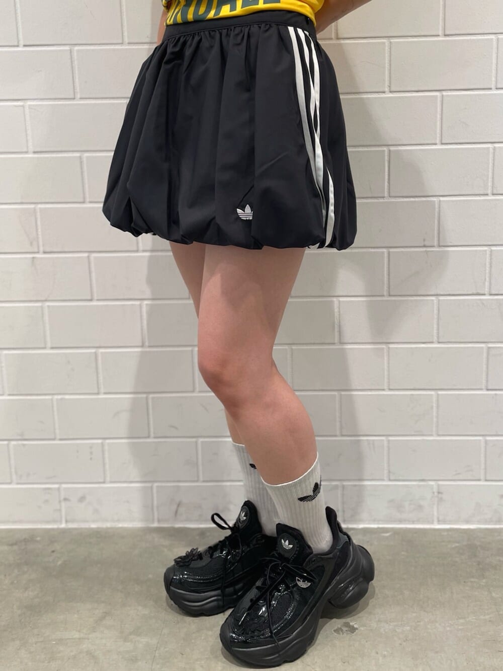 ブラック系のスカート、イエロー系のトップス、ブラック系のスニーカーを着用したレディースの冬コーディネートの5枚目の写真