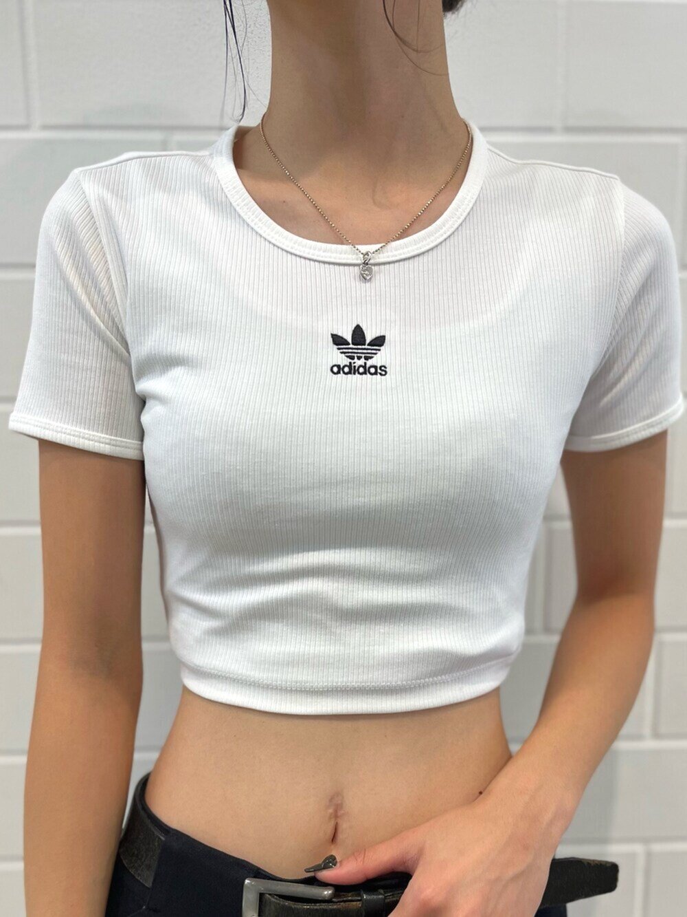 ホワイト系のTシャツ/カットソー、ブラック系のスニーカー、ブラック系のダウンジャケット/コートを着用したレディースの秋コーディネートの5枚目の写真