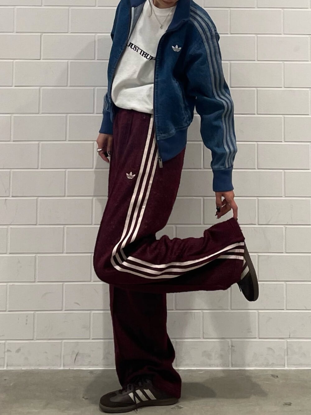 ブルー系のデニムジャケット、ベージュ系のショルダーバッグ、レッド系のスウェットパンツを着用したレディースの秋コーディネートの2枚目の写真