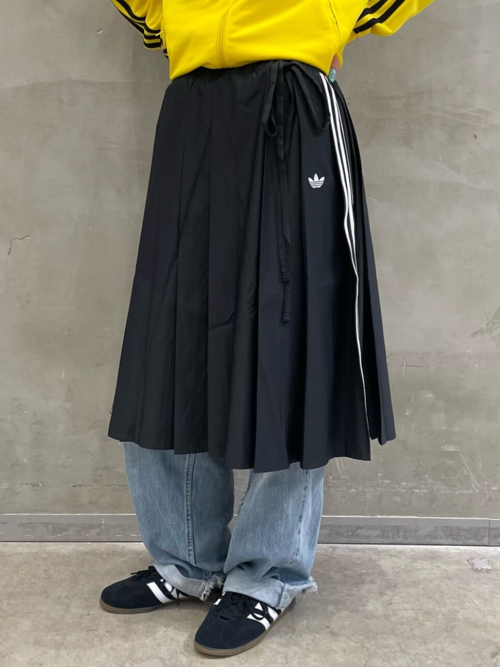 ブラック系のスカート、イエロー系のジャージ、ブラック系のスニーカーを着用したレディースの夏コーディネートの5枚目の写真