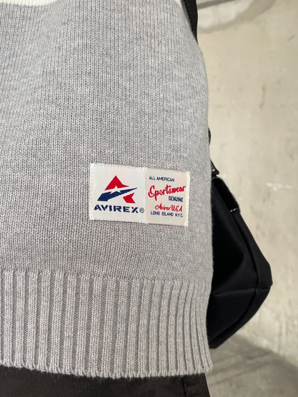 グレー系のニット/セーター、ブラック系のショルダーバッグ、ホワイト系のパンツを着用したメンズの冬コーディネートの3枚目の写真