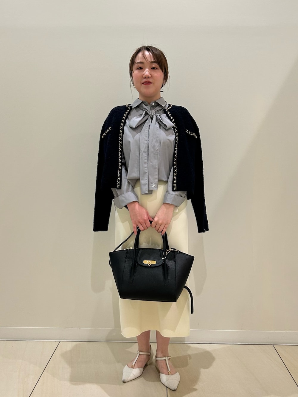 ブルー系のカーディガン/ボレロ、グレー系のシャツ/ブラウス、ホワイト系のスカートを着用したレディースの秋コーディネートの2枚目の写真