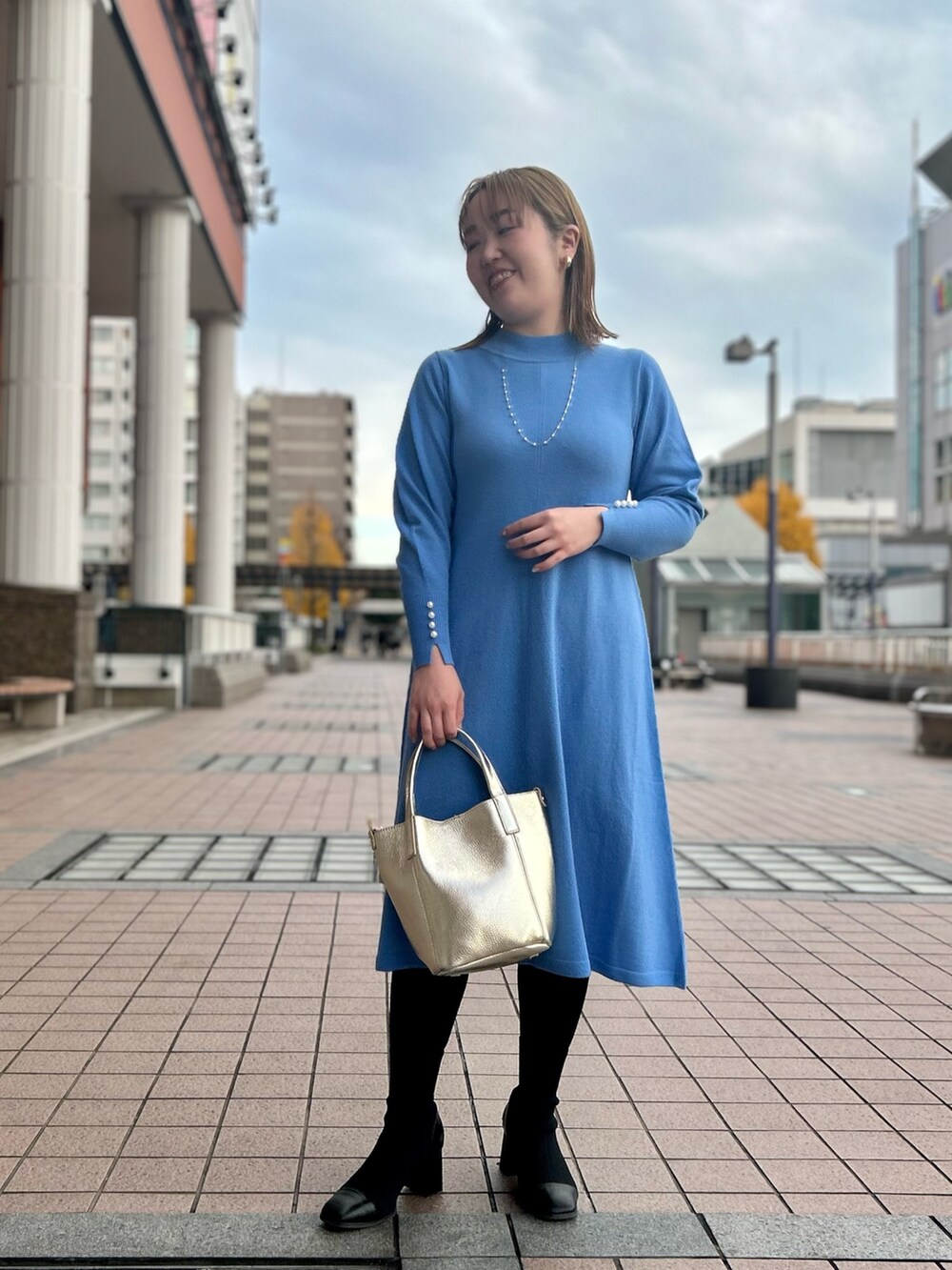 ブルー系のワンピース、ゴールド系のトートバッグ、ゴールド系のイヤリングを着用したレディースの冬コーディネートの6枚目の写真