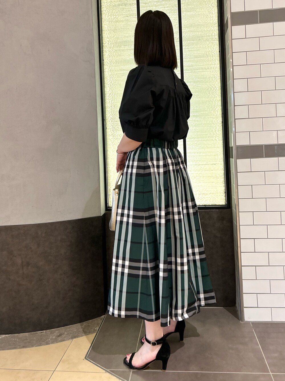 ブラック系のシャツ/ブラウス、グリーン系のスカート、ホワイト系のトートバッグを着用したレディースの夏コーディネートの4枚目の写真