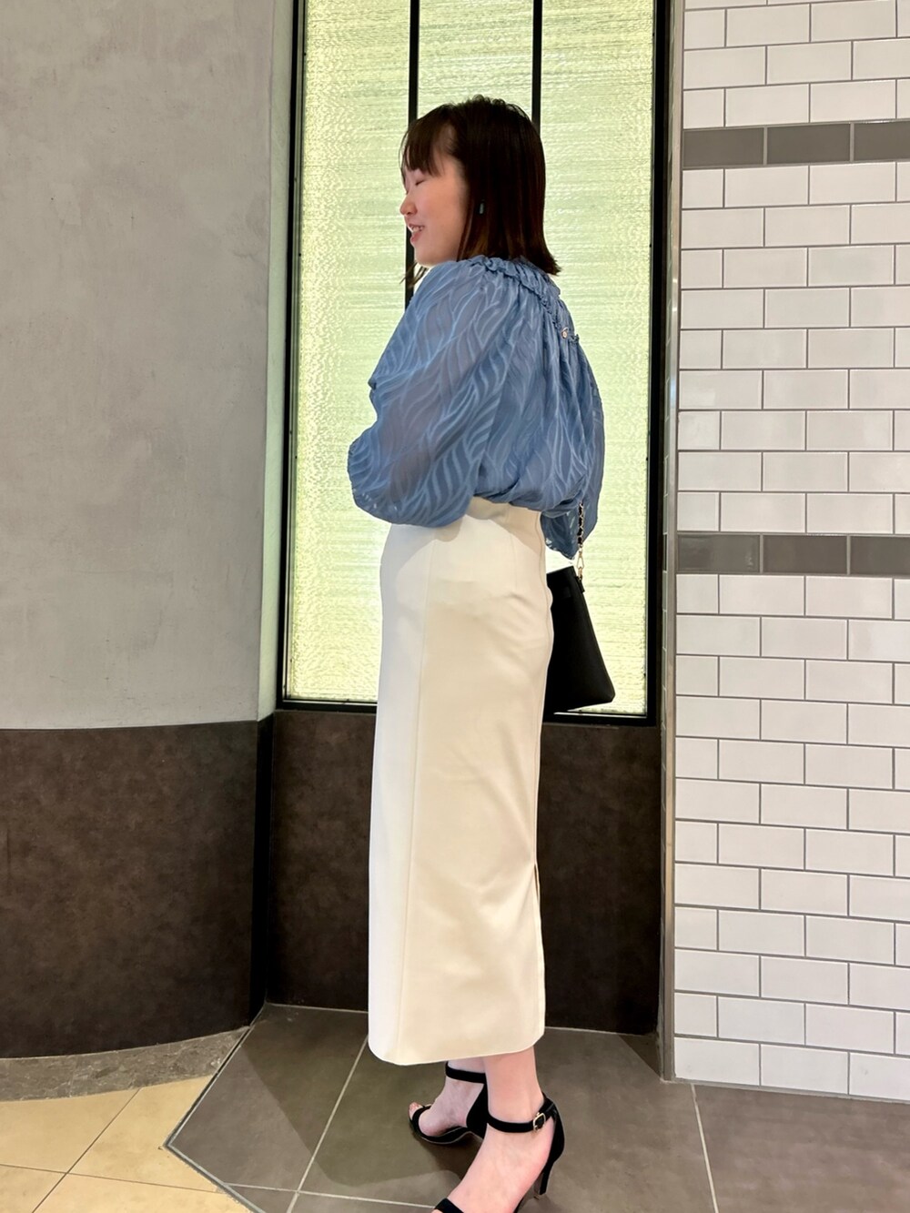 ブルー系のシャツ/ブラウス、ブラック系のショルダーバッグ、ホワイト系のスカートを着用したレディースの夏コーディネートの3枚目の写真