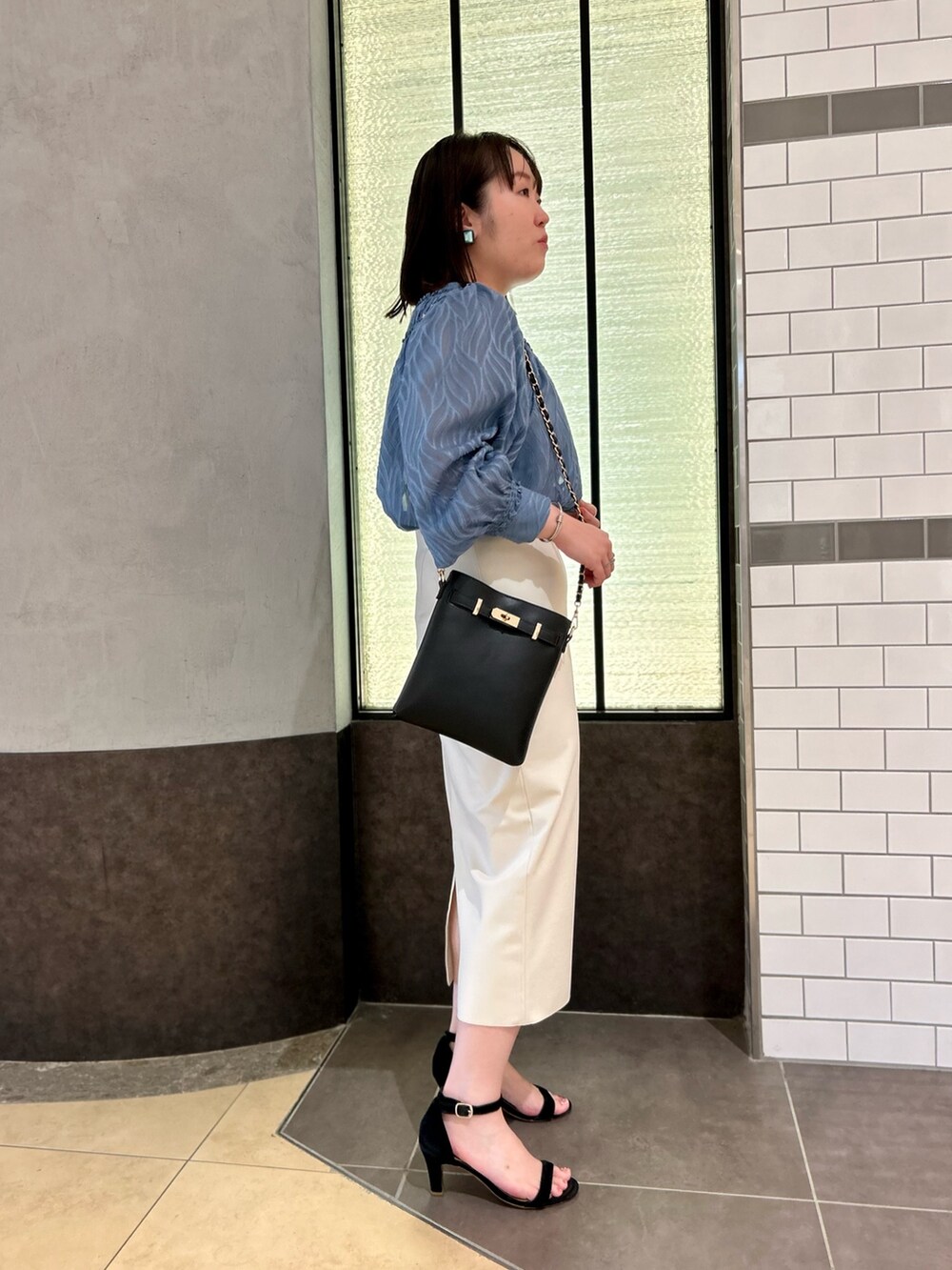 ブルー系のシャツ/ブラウス、ブラック系のショルダーバッグ、ホワイト系のスカートを着用したレディースの夏コーディネートの5枚目の写真