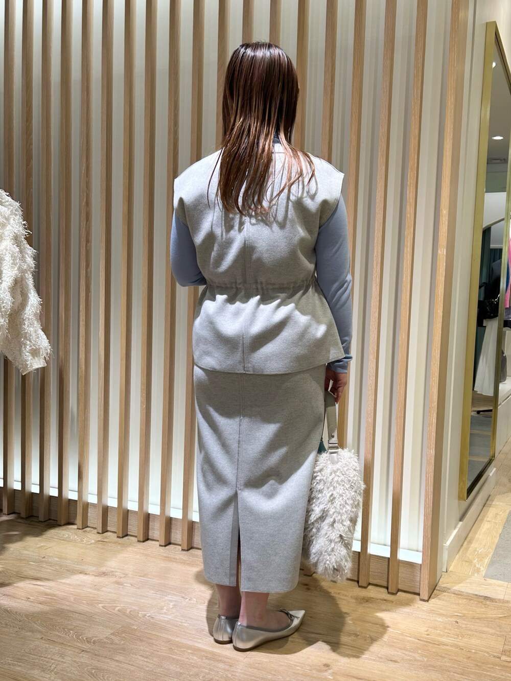 グレー系のベスト、グレー系のスカート、ブルー系のニット/セーターを着用したレディースの冬コーディネートの3枚目の写真