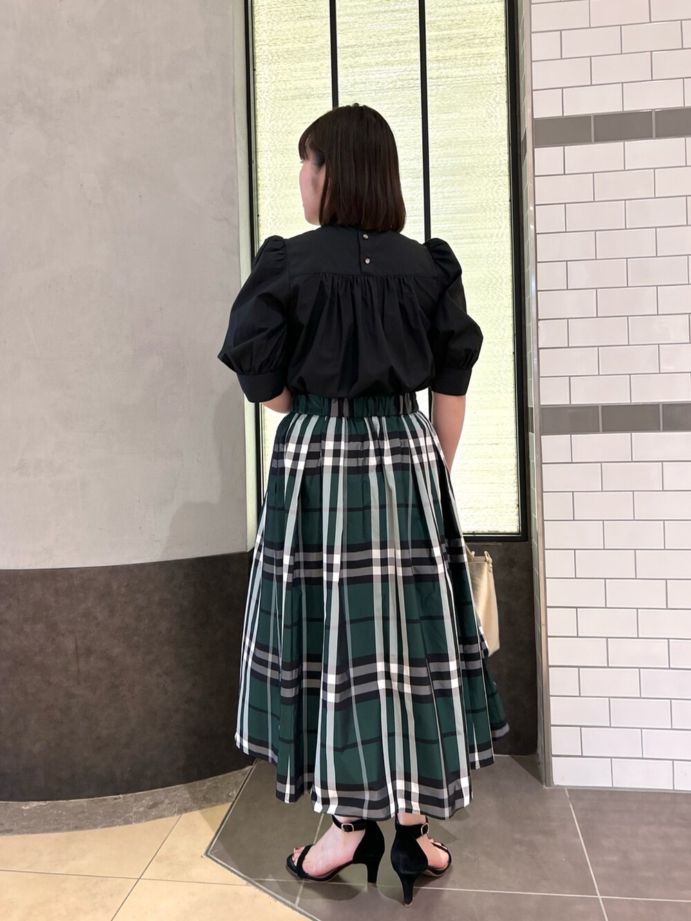 ブラック系のシャツ/ブラウス、グリーン系のスカート、ホワイト系のトートバッグを着用したレディースの夏コーディネートの5枚目の写真