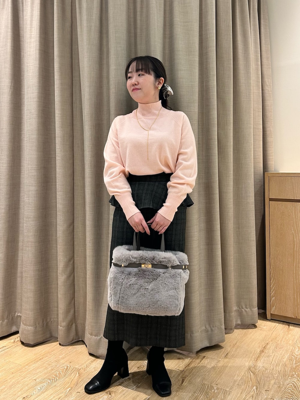 ピンク系のニット/セーター、ブラック系のスカート、ベージュ系のトートバッグを着用したレディースの冬コーディネートの9枚目の写真