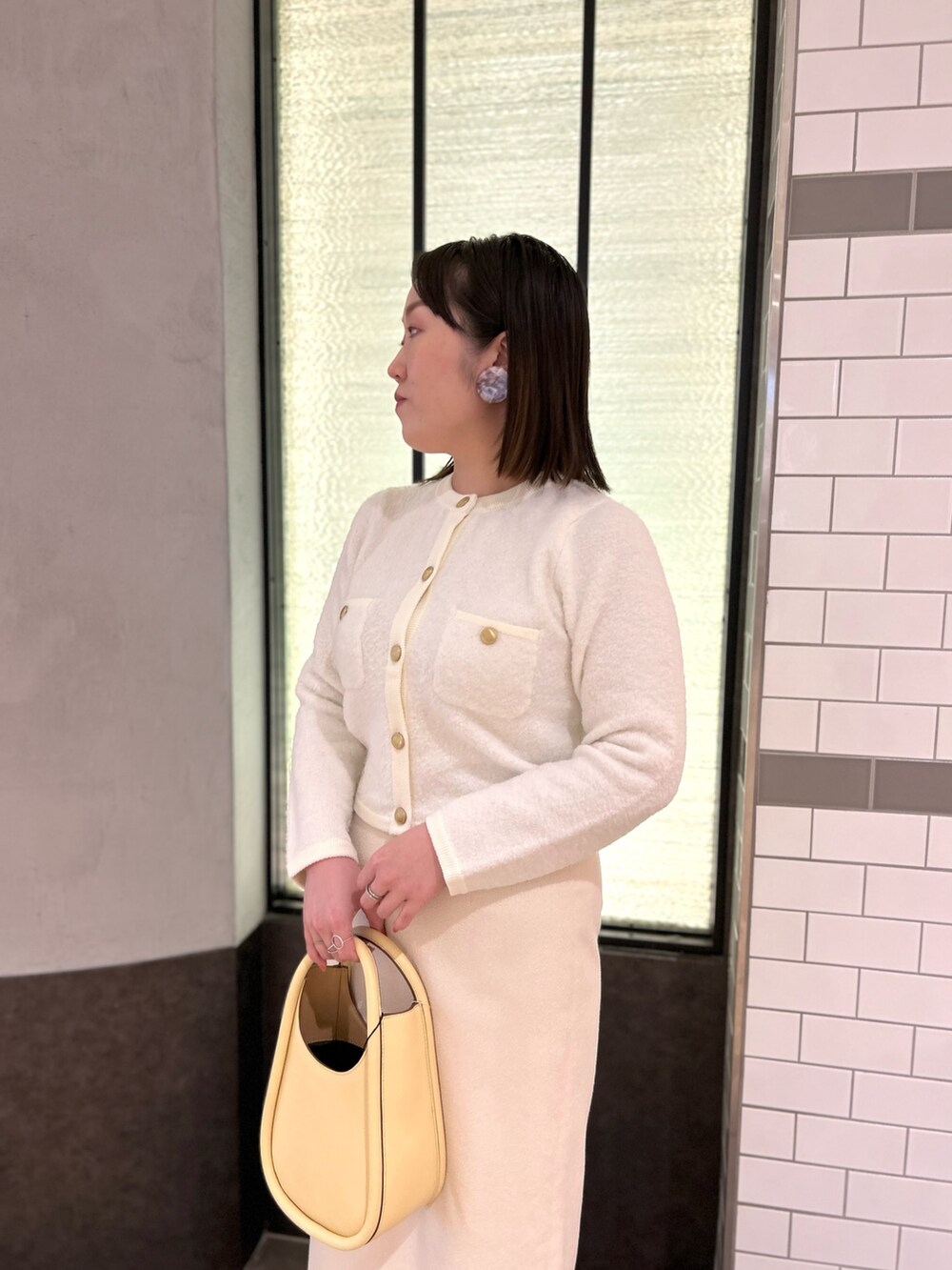 ホワイト系のカーディガン/ボレロ、ホワイト系のスカート、イエロー系のハンドバッグを着用したレディースの秋コーディネートの8枚目の写真