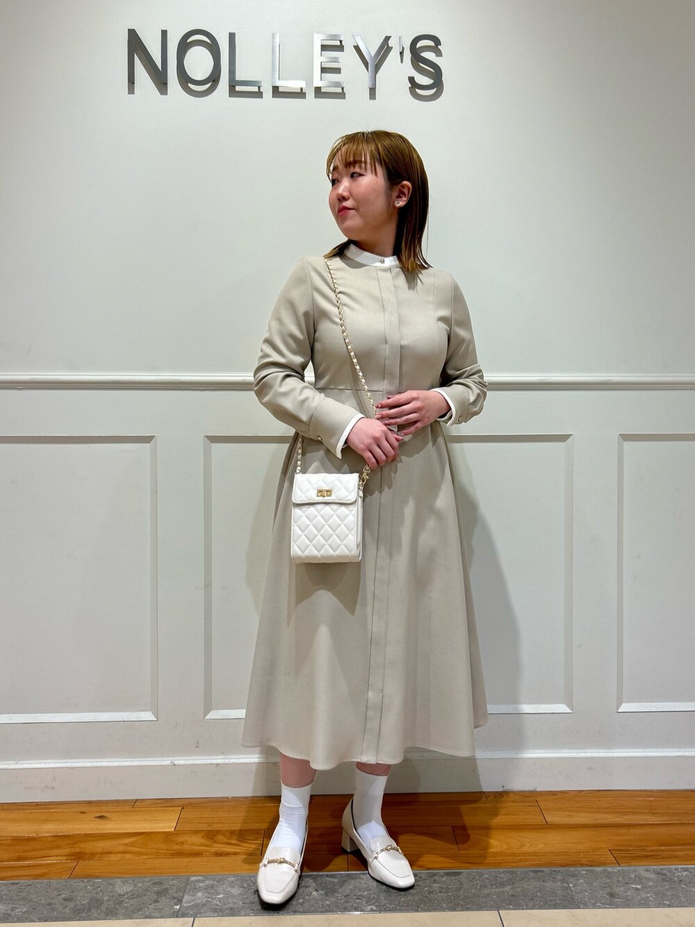 ベージュ系のワンピース、ホワイト系のショルダーバッグ、ホワイト系のイヤリングを着用したレディースの冬コーディネートの6枚目の写真