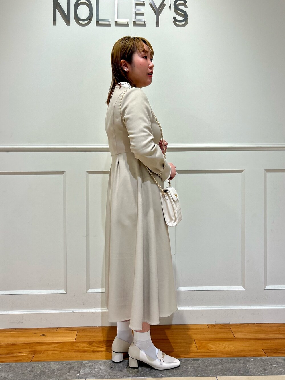 ベージュ系のワンピース、ホワイト系のショルダーバッグ、ホワイト系のイヤリングを着用したレディースの冬コーディネートの5枚目の写真