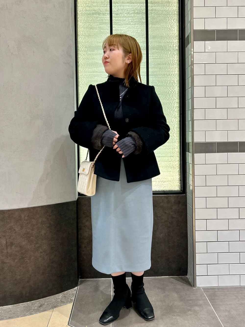 ブラック系のその他アウター、グレー系のニット/セーター、ブルー系のスカートを着用したレディースの冬コーディネートの2枚目の写真