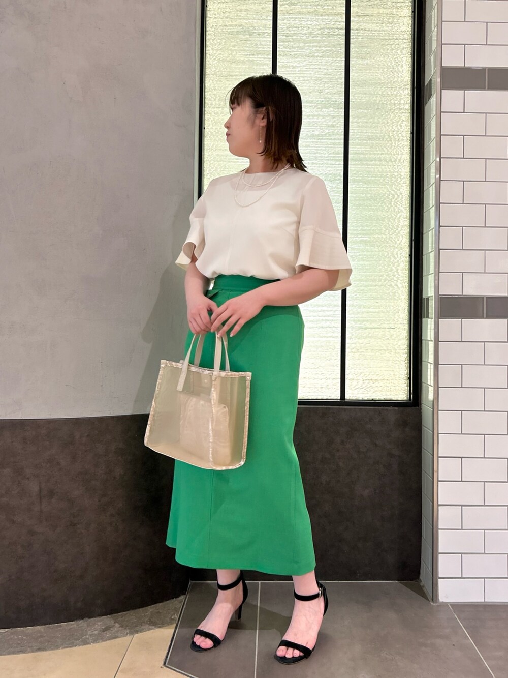 ベージュ系のトートバッグ、ホワイト系のシャツ/ブラウス、グリーン系のスカートを着用したレディースの春コーディネートの5枚目の写真