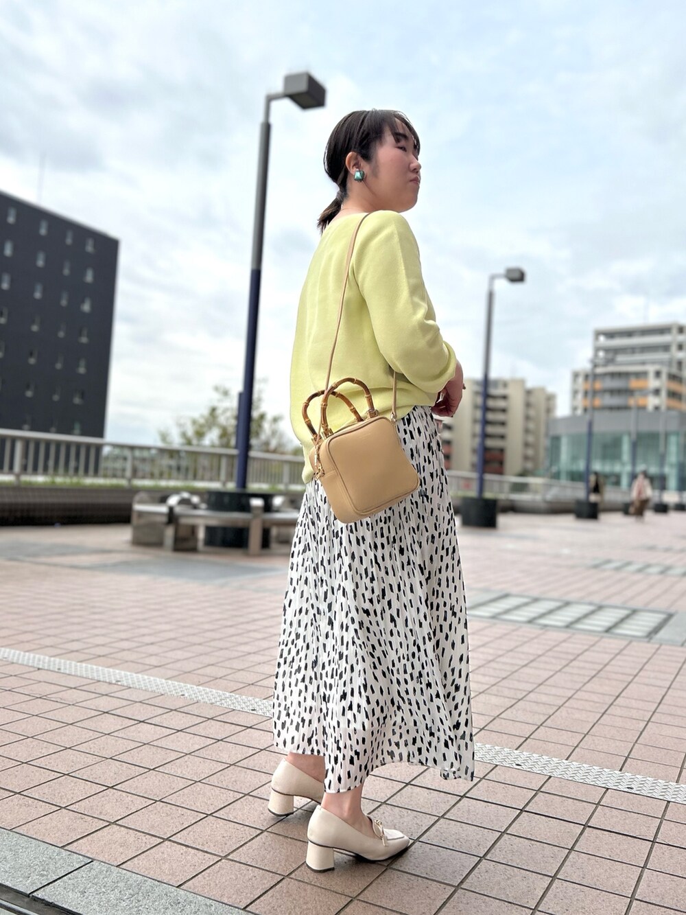 ホワイト系のスカート、ベージュ系のハンドバッグ、イエロー系のニット/セーターを着用したレディースの春コーディネートの4枚目の写真