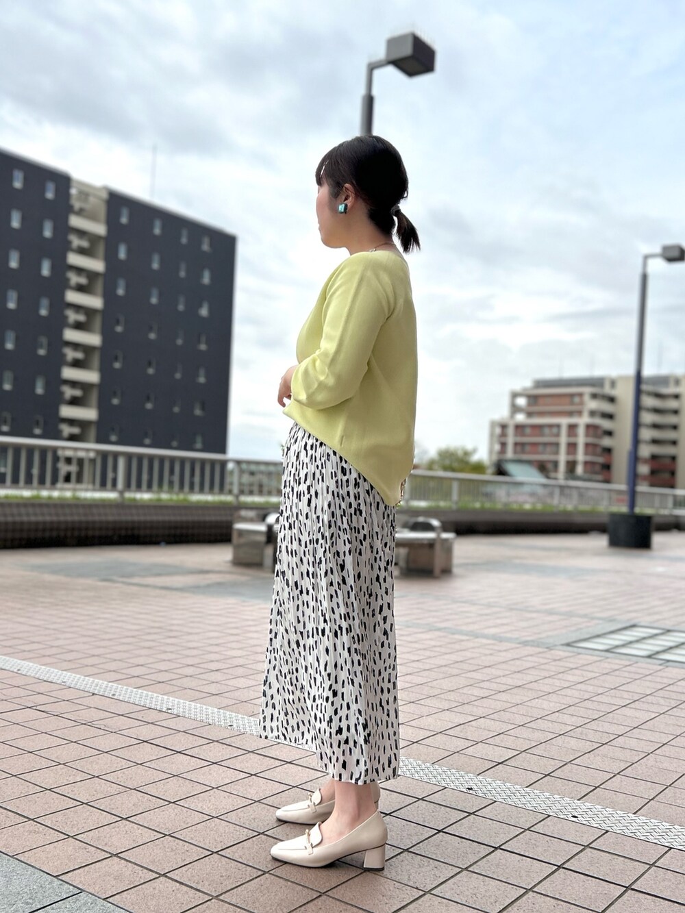 ホワイト系のスカート、ベージュ系のハンドバッグ、イエロー系のニット/セーターを着用したレディースの春コーディネートの3枚目の写真