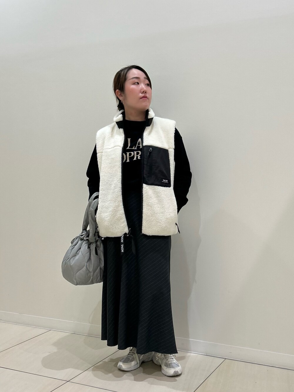 ホワイト系のダウンベスト、ブラック系のカーディガン/ボレロ、グリーン系のトートバッグを着用したレディースの冬コーディネートの10枚目の写真