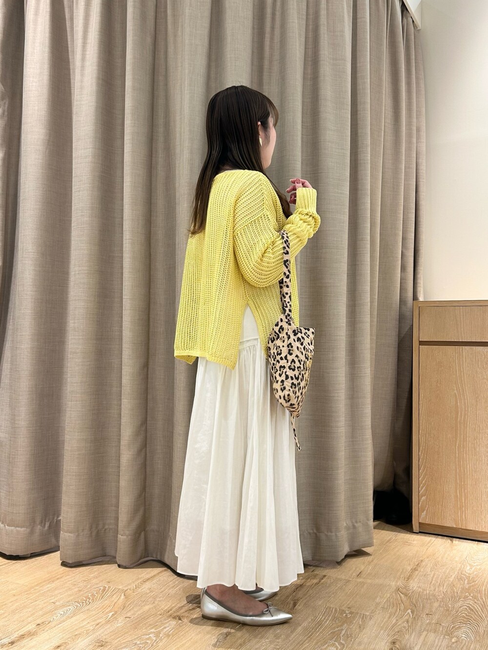 イエロー系のニット/セーター、ホワイト系のTシャツ/カットソー、ホワイト系のスカートを着用したレディースの春コーディネートの4枚目の写真