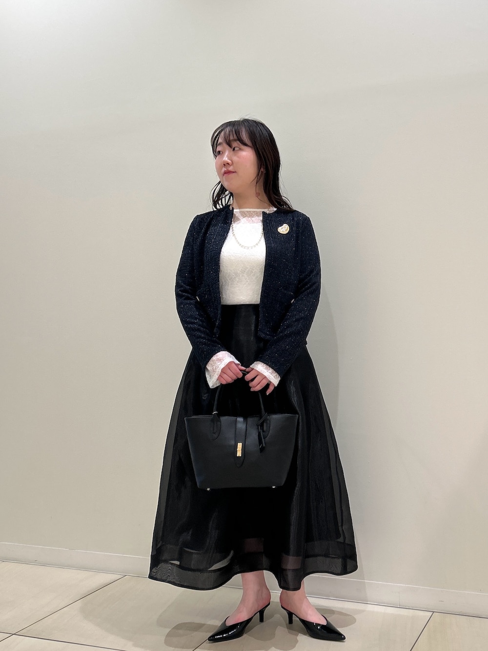 ブルー系のノーカラージャケット、ブラック系のスカート、ホワイト系のTシャツ/カットソーを着用したレディースの春コーディネートの5枚目の写真