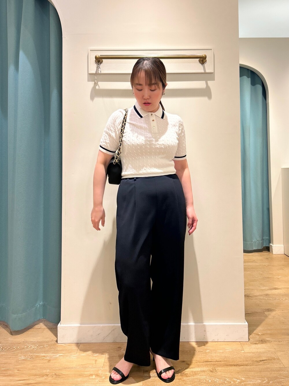 ホワイト系のニット/セーター、ブルー系のその他パンツ、ブラック系のショルダーバッグを着用したレディースの夏コーディネートの2枚目の写真