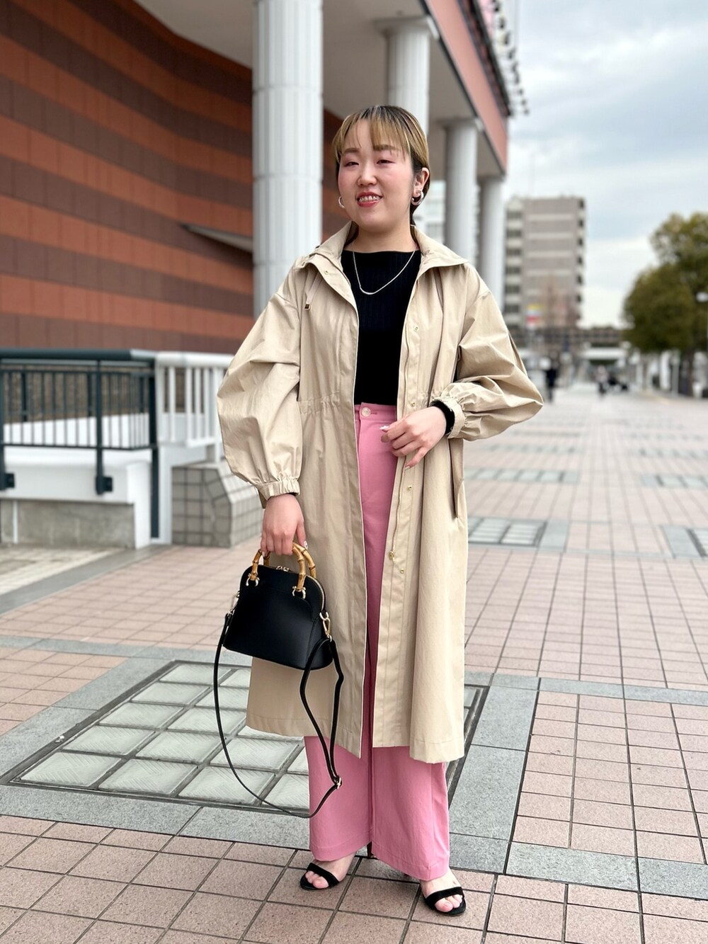 ベージュ系のその他アウター、ブラック系のニット/セーター、ピンク系のチノパンツを着用したレディースの春コーディネートの7枚目の写真