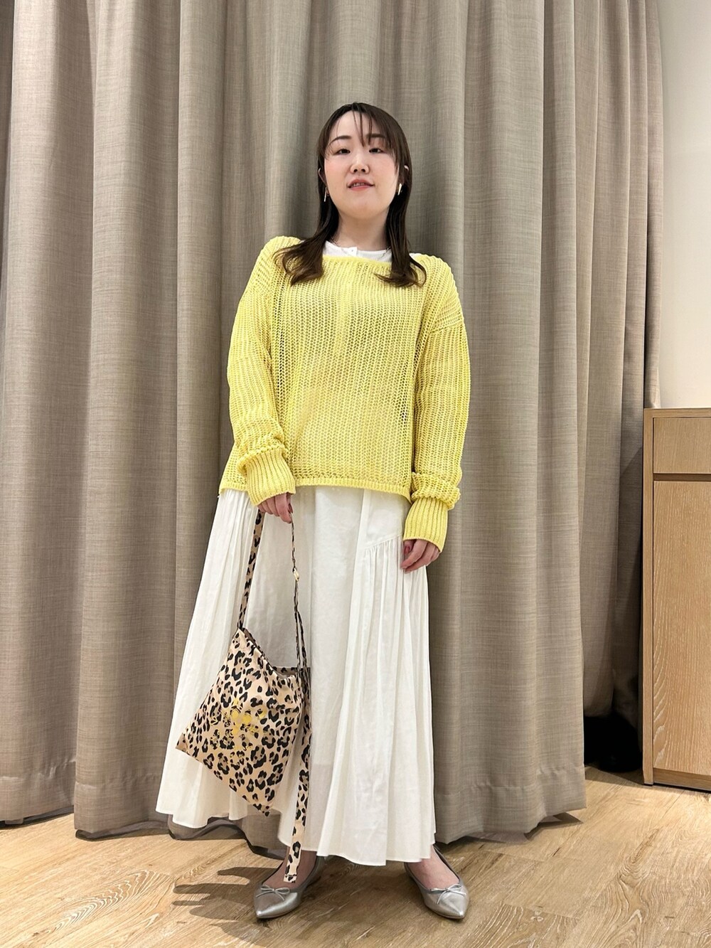 イエロー系のニット/セーター、ホワイト系のTシャツ/カットソー、ホワイト系のスカートを着用したレディースの春コーディネートの6枚目の写真