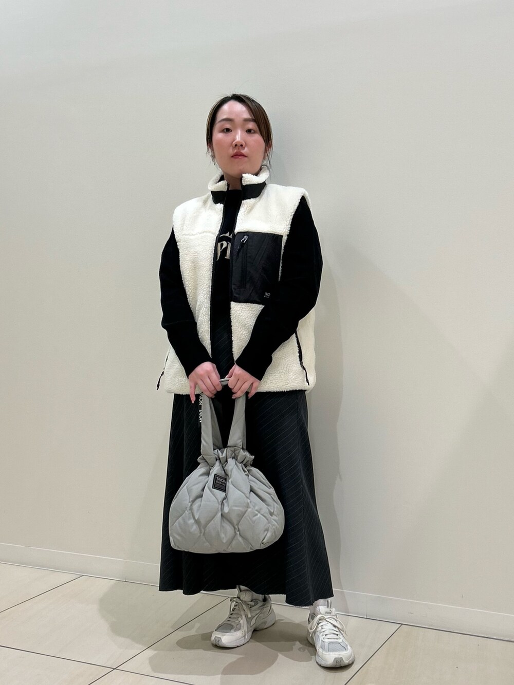 ホワイト系のダウンベスト、ブラック系のカーディガン/ボレロ、グリーン系のトートバッグを着用したレディースの冬コーディネートの8枚目の写真