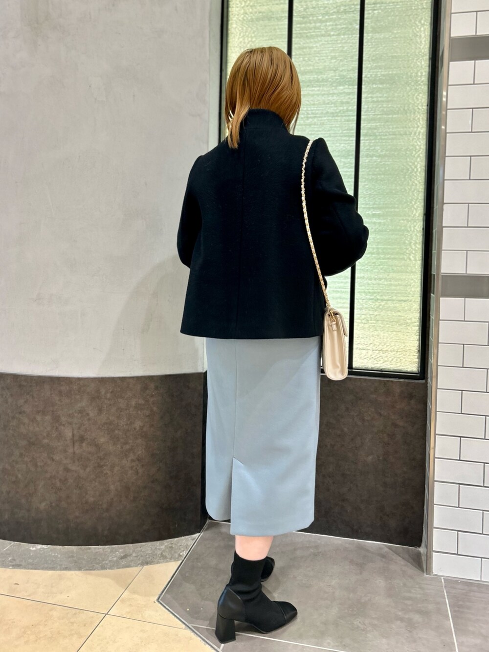 ブラック系のその他アウター、グレー系のニット/セーター、ブルー系のスカートを着用したレディースの冬コーディネートの4枚目の写真
