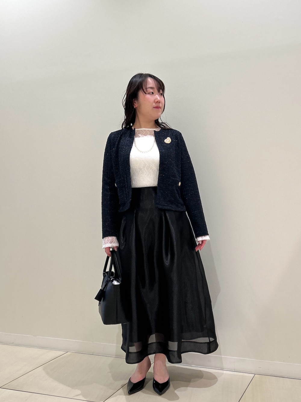 ブルー系のノーカラージャケット、ブラック系のスカート、ホワイト系のTシャツ/カットソーを着用したレディースの春コーディネートの10枚目の写真