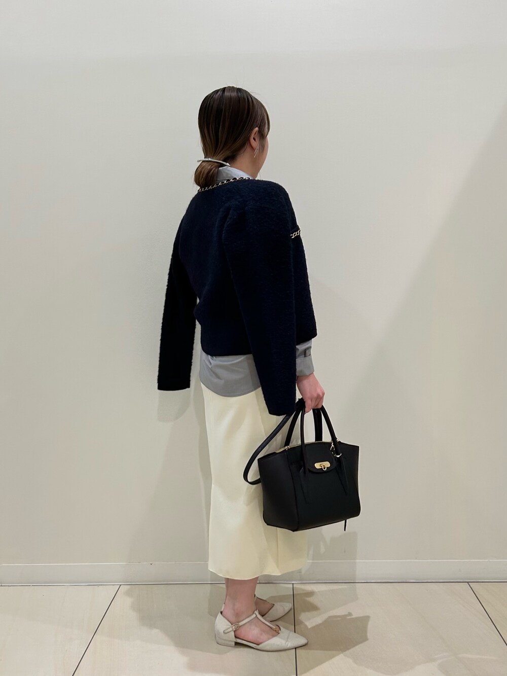 ブルー系のカーディガン/ボレロ、グレー系のシャツ/ブラウス、ホワイト系のスカートを着用したレディースの秋コーディネートの4枚目の写真