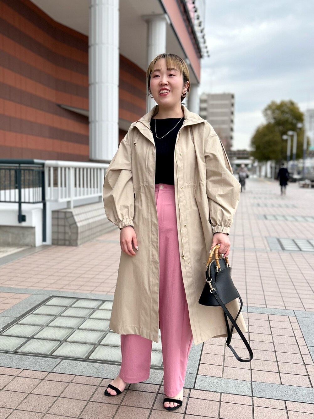 ベージュ系のその他アウター、ブラック系のニット/セーター、ピンク系のチノパンツを着用したレディースの春コーディネートの8枚目の写真