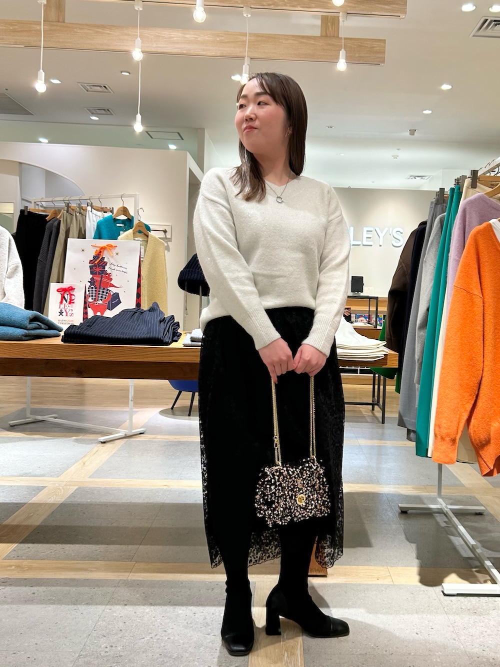 ホワイト系のニット/セーター、ブラック系のスカート、その他のショルダーバッグを着用したレディースの冬コーディネートの5枚目の写真