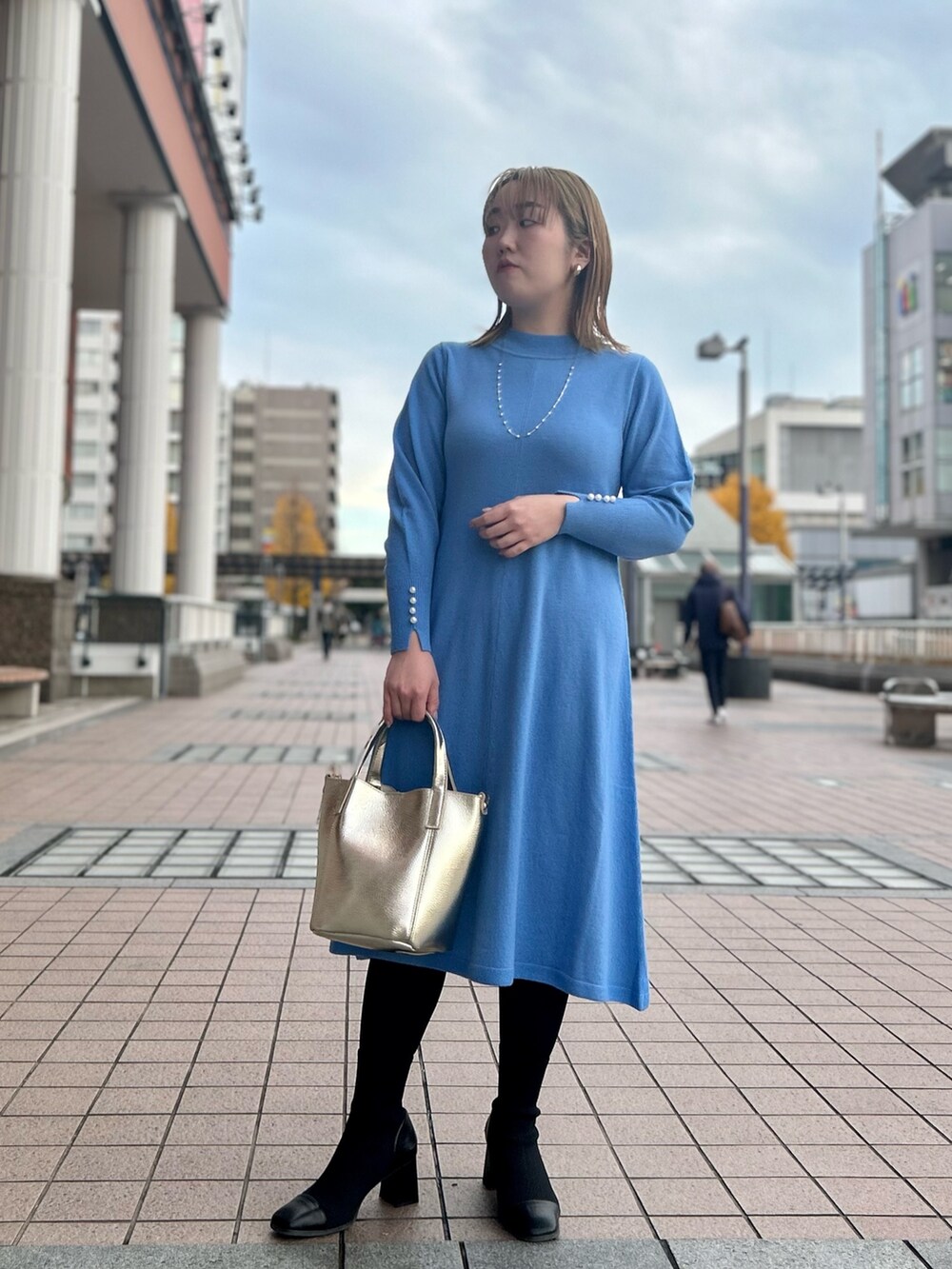 ブルー系のワンピース、ゴールド系のトートバッグ、ゴールド系のイヤリングを着用したレディースの冬コーディネートの10枚目の写真
