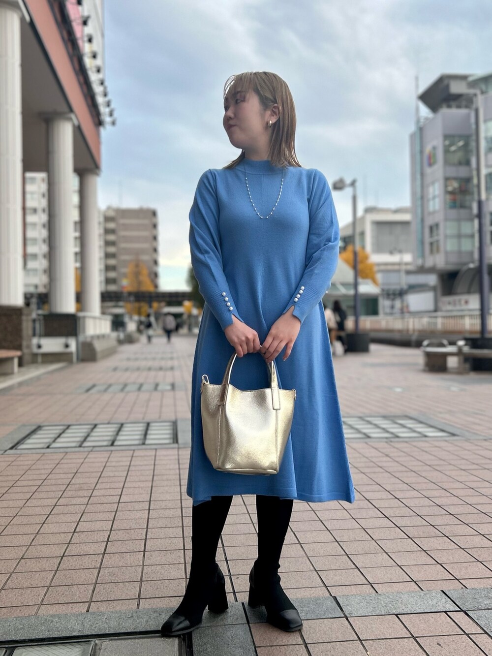 ブルー系のワンピース、ゴールド系のトートバッグ、ゴールド系のイヤリングを着用したレディースの冬コーディネートの2枚目の写真