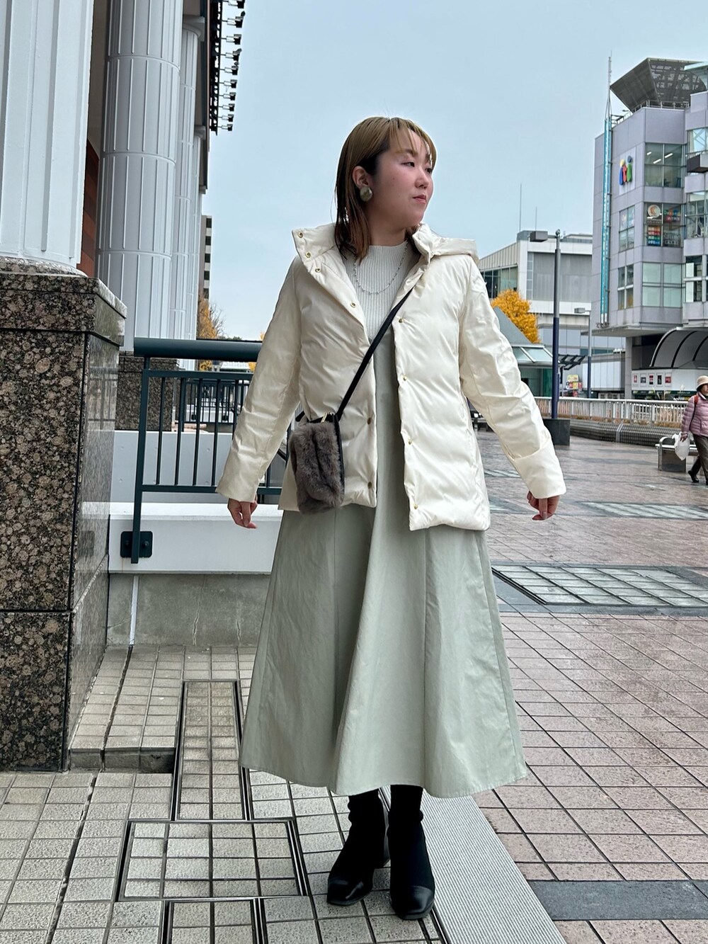 ホワイト系のダウンジャケット/コート、グレー系のワンピース、シルバー系のニット/セーターを着用したレディースの冬コーディネートの9枚目の写真