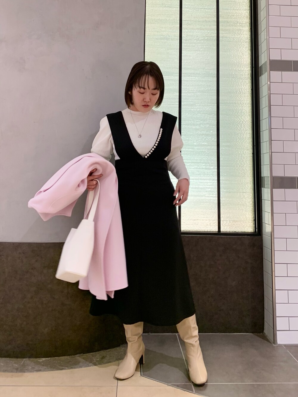 ブラック系のワンピース、ホワイト系のニット/セーター、ホワイト系のトートバッグを着用したレディースの冬コーディネートの2枚目の写真