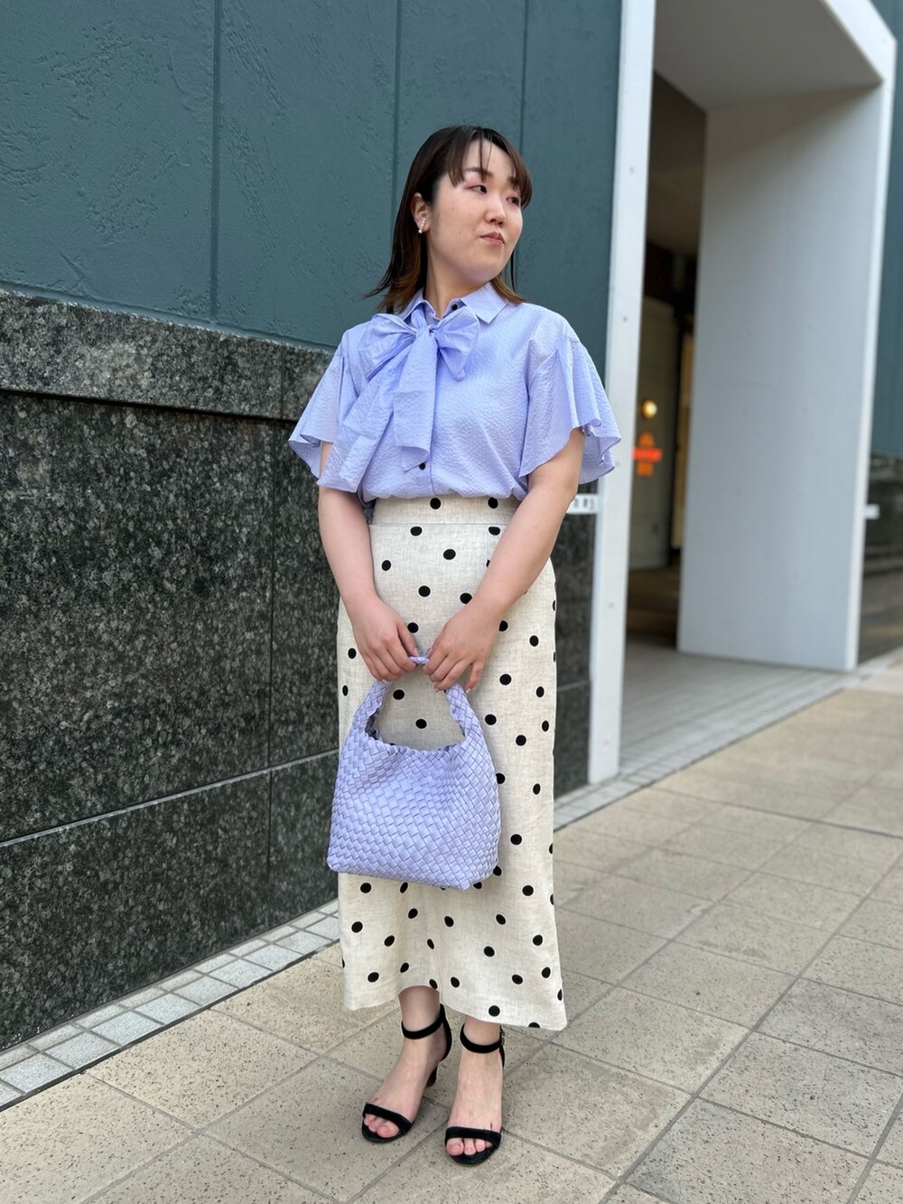 パープル系のシャツ/ブラウス、ベージュ系のスカート、パープル系のショルダーバッグを着用したレディースの春コーディネートの2枚目の写真