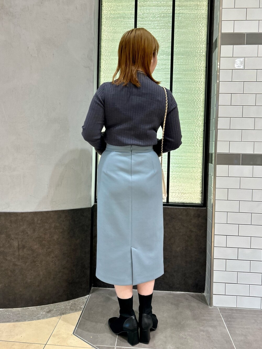 グレー系のニット/セーター、ブルー系のスカート、ホワイト系のショルダーバッグを着用したレディースの冬コーディネートの4枚目の写真