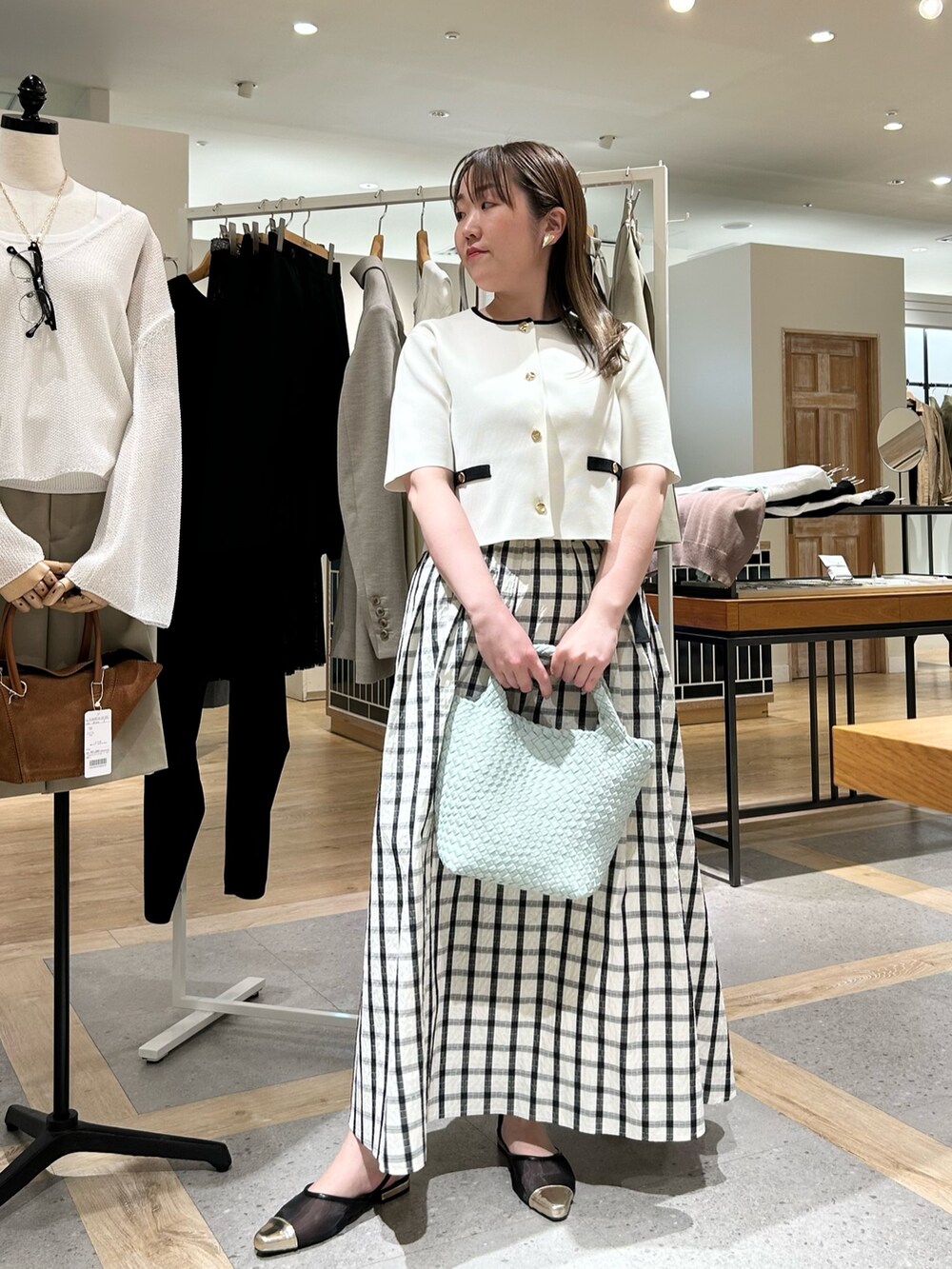 ホワイト系のノーカラージャケット、グリーン系のショルダーバッグ、ゴールド系のイヤリングを着用したレディースの夏コーディネートの9枚目の写真