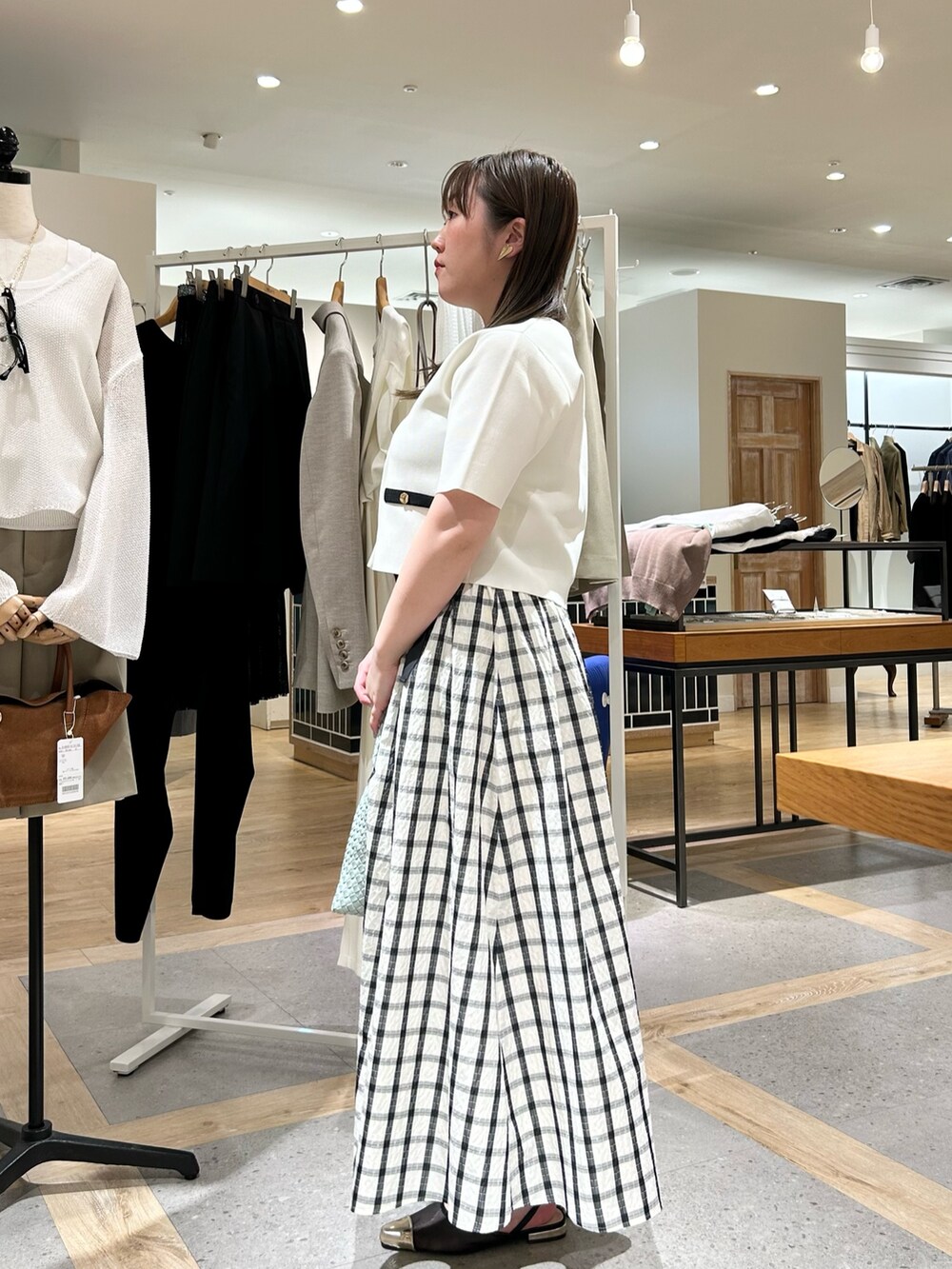 ホワイト系のノーカラージャケット、グリーン系のショルダーバッグ、ゴールド系のイヤリングを着用したレディースの夏コーディネートの2枚目の写真