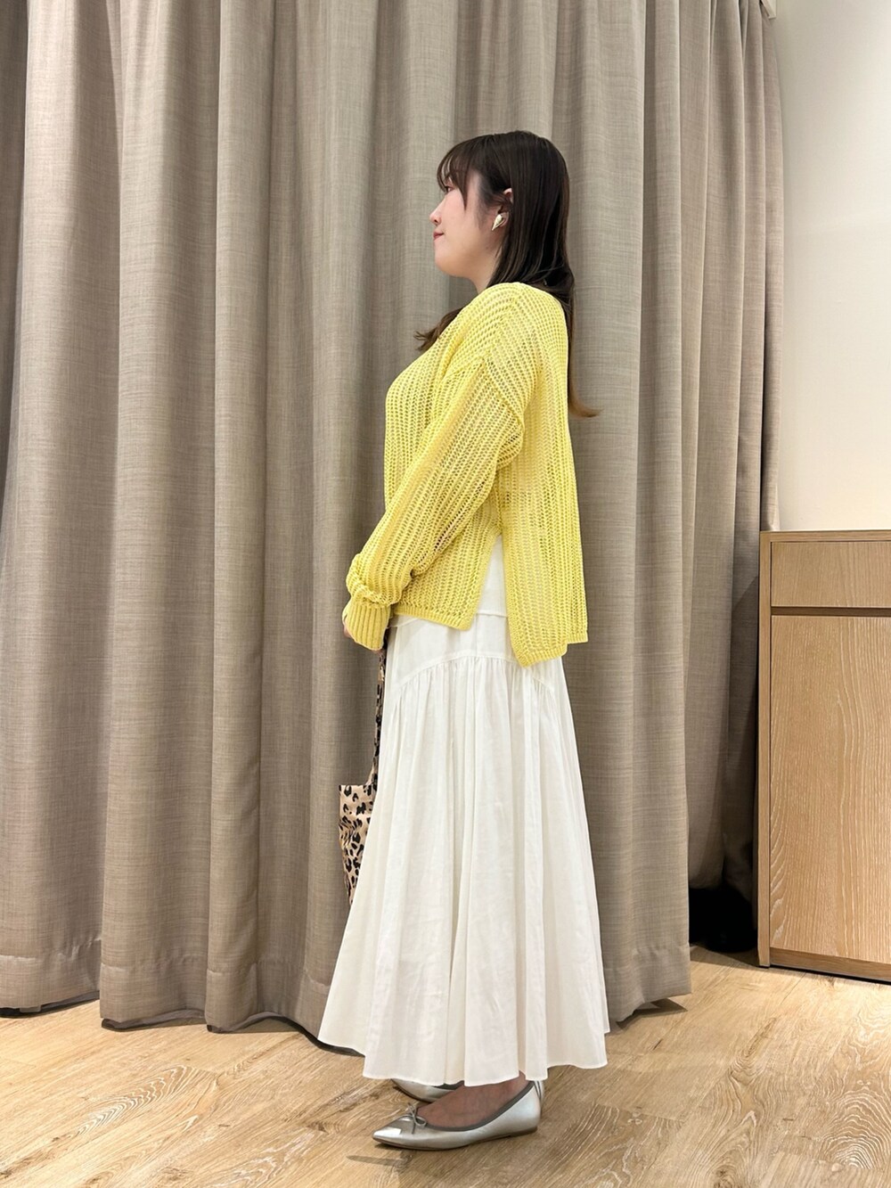 イエロー系のニット/セーター、ホワイト系のTシャツ/カットソー、ホワイト系のスカートを着用したレディースの春コーディネートの2枚目の写真