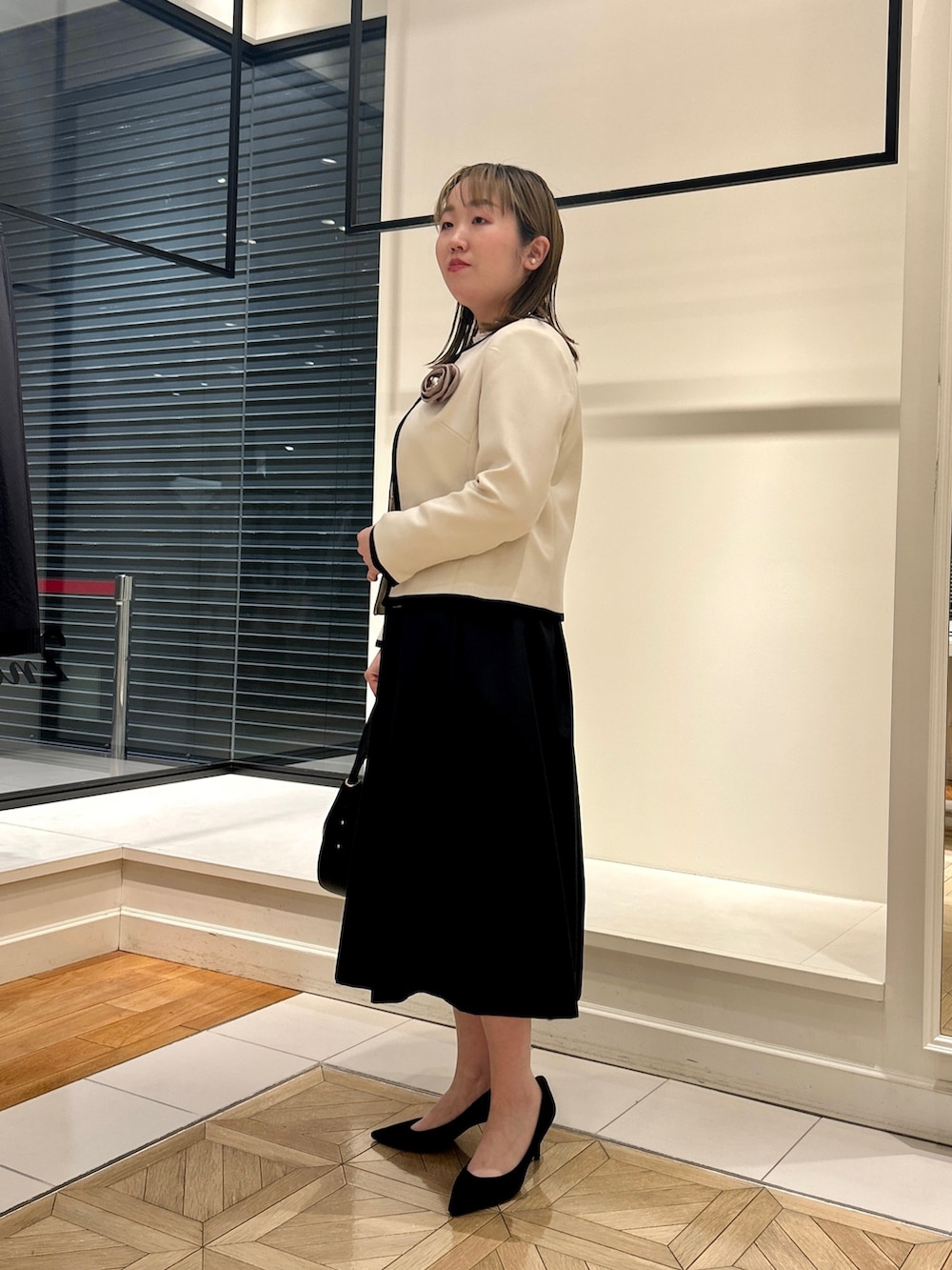 ホワイト系のノーカラージャケット、ホワイト系のシャツ/ブラウス、ブラック系のショルダーバッグを着用したレディースの冬コーディネートの3枚目の写真