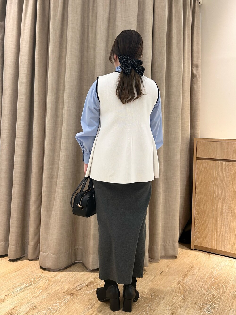 ホワイト系のベスト、ブルー系のシャツ/ブラウス、グレー系のスカートを着用したレディースの冬コーディネートの3枚目の写真