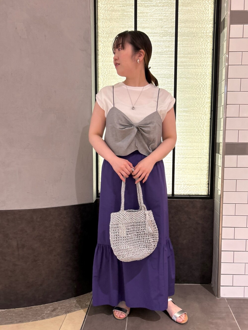 グレー系のTシャツ/カットソー、パープル系のスカート、シルバー系のバックパック/リュックを着用したレディースの夏コーディネートの9枚目の写真